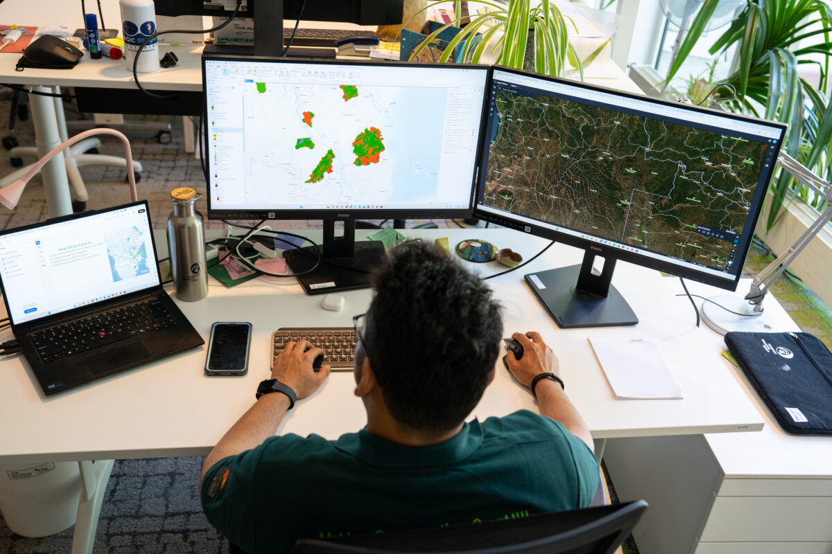 Shanyal Uqaili arbeitet an mehreren Bildschirmen mit Satellitenkarten und Geodaten zur Analyse und Überwachung von Schutzgebieten.