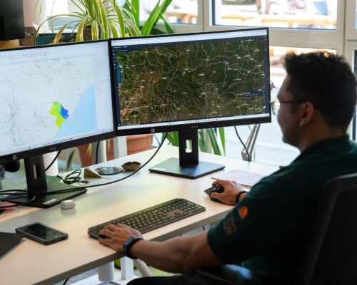 Shanyal Uqaili arbeitet an zwei Bildschirmen mit Satellitenkarten und Geodaten zur Analyse von Schutzgebieten.