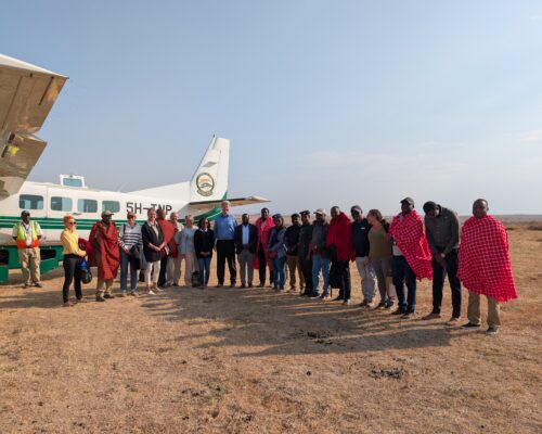 Members of the visiting delegation and Tanzanian hosts stand together beside an aircraft in northern Tanzania.