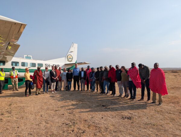 Members of the visiting delegation and Tanzanian hosts stand together beside an aircraft in northern Tanzania.