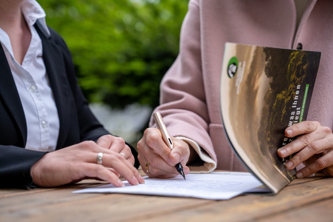 Menschen sitzen am Tisch und schreiben ein Testament.